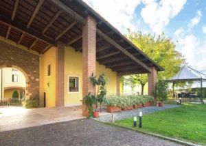 Giardino residence La Mason con portico, a lato un gazebo dove rilassarsi e accesso frontale al chiostro ed agli appartamenti